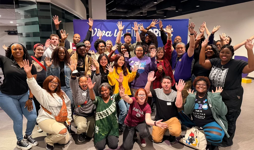 Students with hands raised pose for a class photo.