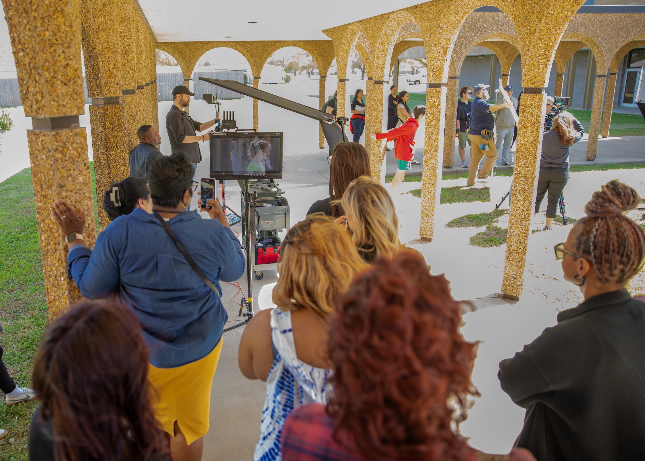 Students on set gathered around a monitor.
