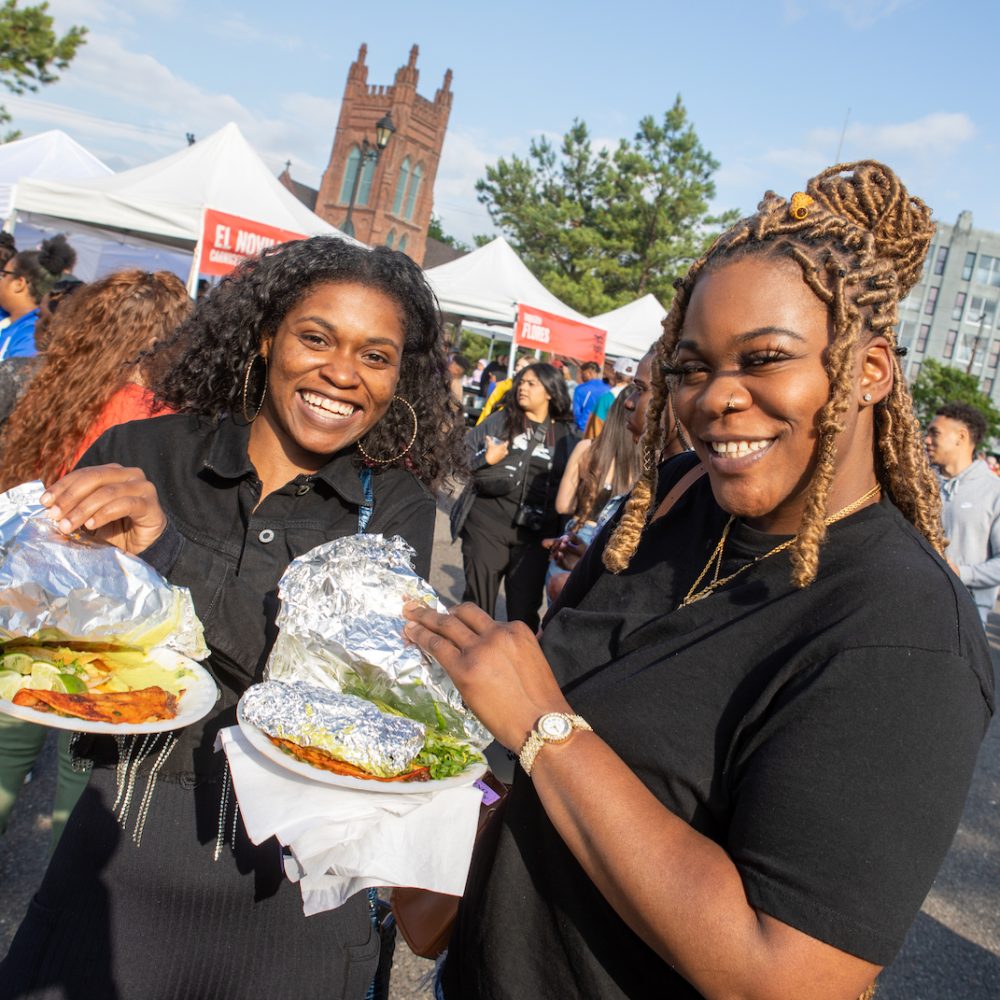 Two black women show off their taco plates.
